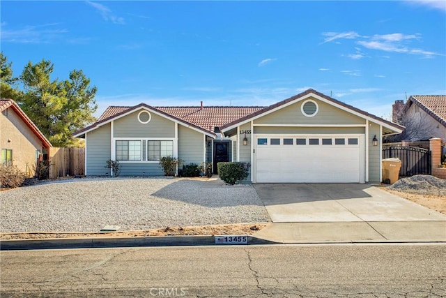 single story home with concrete driveway, an attached garage, a tile roof, and fence