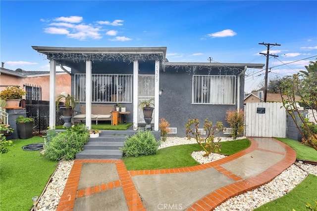 view of front of house featuring a front yard, fence, a gate, and stucco siding