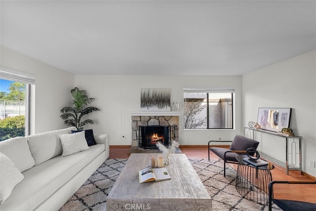 living room with light wood-style floors, baseboards, and a stone fireplace