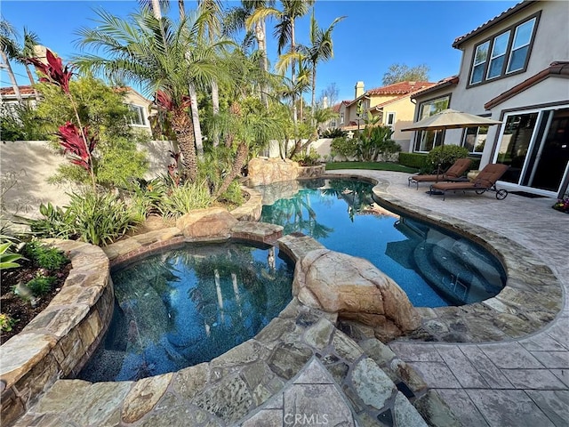 view of pool featuring a pool with connected hot tub, fence, and a patio