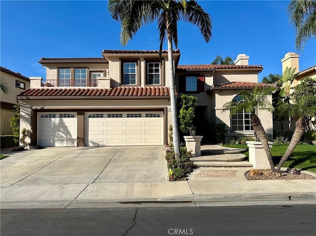 mediterranean / spanish home featuring stucco siding, an attached garage, a balcony, driveway, and a tiled roof