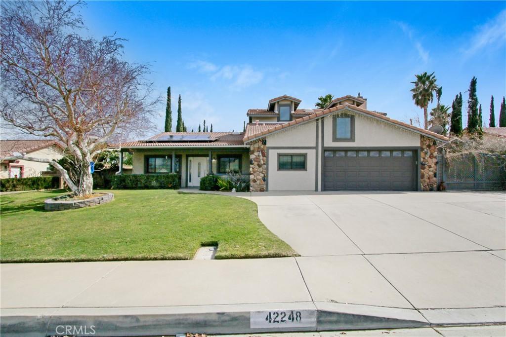 42248 Woodstone Ln, Lancaster, CA 93536 - view of front of house with stucco siding, concrete driveway, an attached garage, roof mounted solar panels, and a front lawn