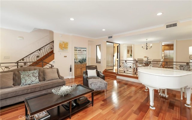 living room featuring light wood-style floors, stairs, visible vents, and crown molding