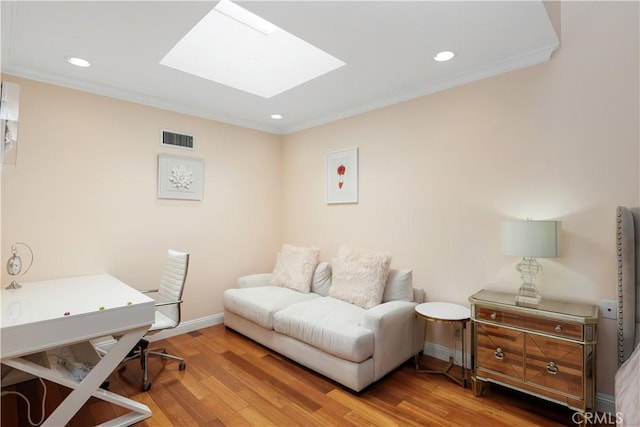 office with ornamental molding, a skylight, visible vents, and wood finished floors