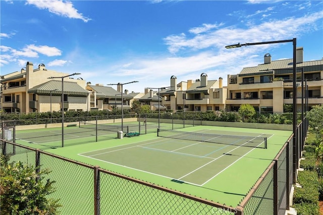 view of tennis court featuring a residential view and fence