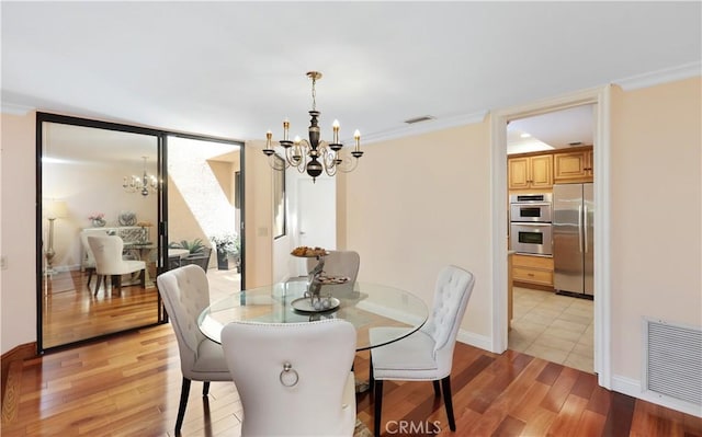 dining area with light wood-style flooring, crown molding, visible vents, and a notable chandelier