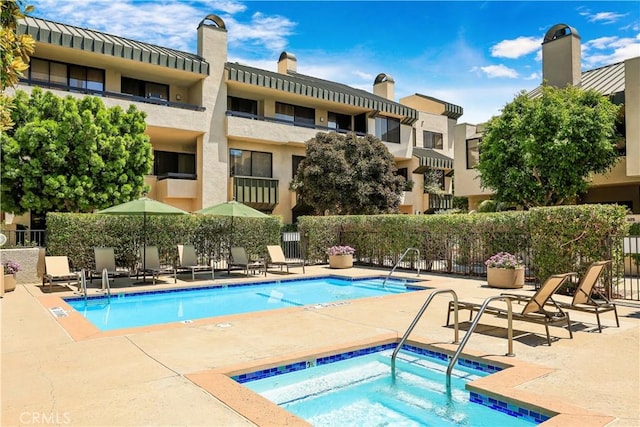 community pool featuring a patio area, a hot tub, and fence