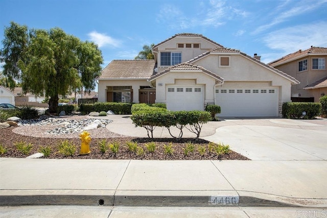 mediterranean / spanish home with an attached garage, driveway, a tiled roof, and stucco siding