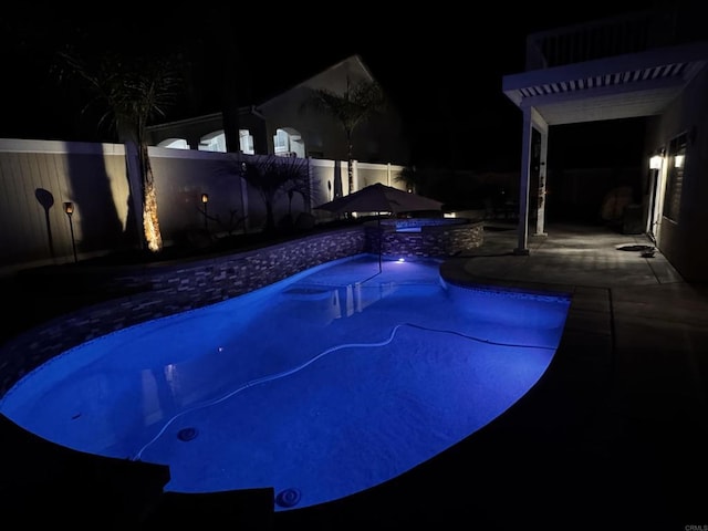 pool at twilight with a fenced backyard and a fenced in pool