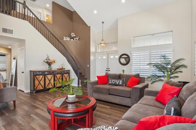 living area with a high ceiling, dark wood-style floors, stairs, and visible vents