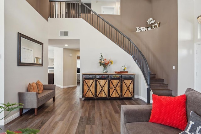 interior space with a high ceiling, visible vents, baseboards, stairs, and dark wood-style floors