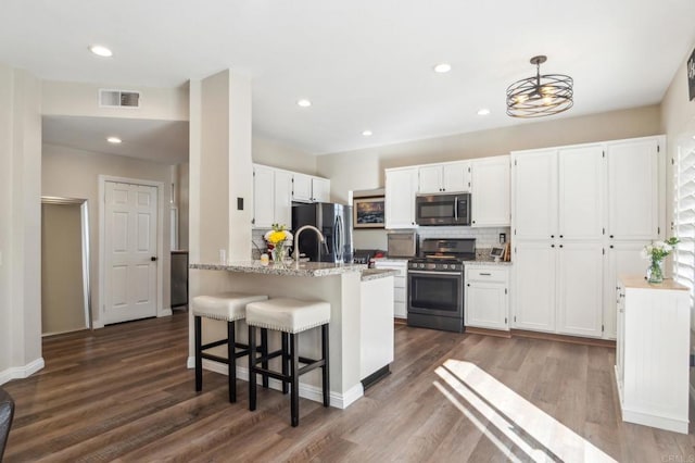 kitchen with hanging light fixtures, light stone countertops, appliances with stainless steel finishes, and white cabinets