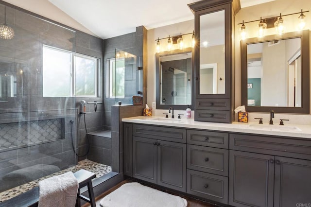 bathroom with double vanity, walk in shower, vaulted ceiling, and a sink