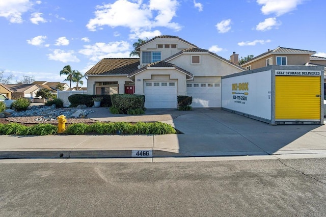 view of front of home with concrete driveway, a tiled roof, an attached garage, and stucco siding