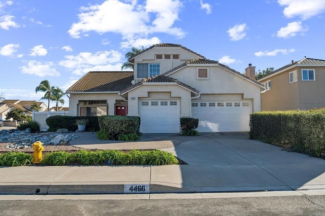 view of front of property featuring an attached garage, a tile roof, concrete driveway, and stucco siding