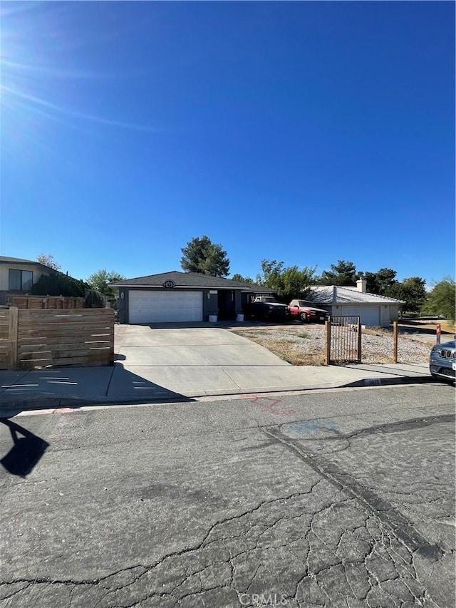 view of front facade featuring concrete driveway, an attached garage, and fence