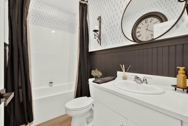 bathroom featuring wainscoting, toilet, wood finished floors, shower / bath combination with curtain, and vanity