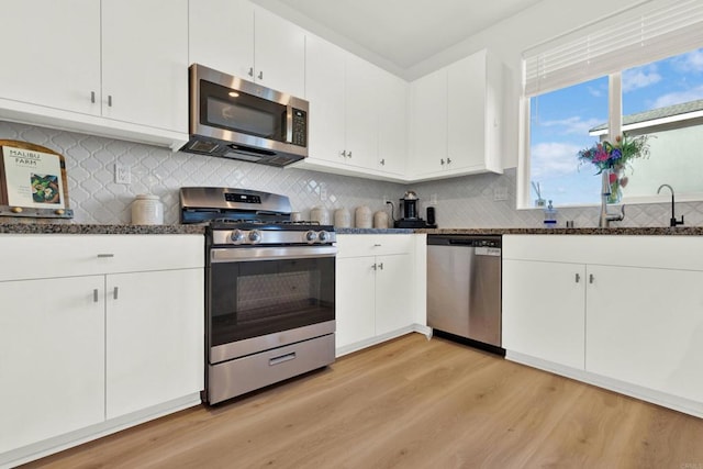 36540 Diego Springs Ave, Murrieta, CA 92563 - kitchen featuring dark stone countertops, white cabinetry, a sink, light wood-style flooring, and stainless steel appliances