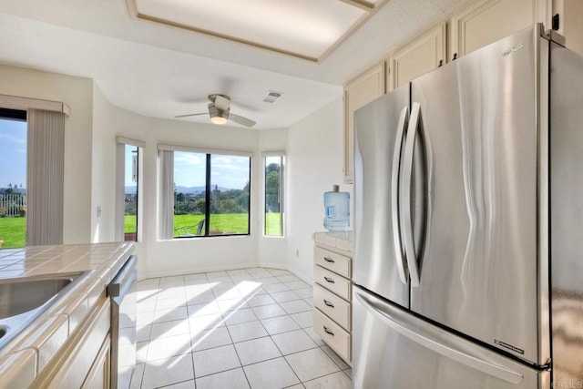 kitchen featuring light tile patterned floors, ceiling fan, stainless steel appliances, visible vents, and tile counters