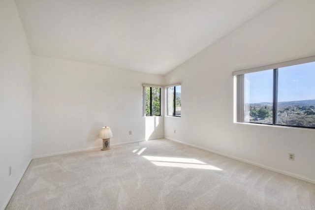 spare room featuring baseboards, vaulted ceiling, and light colored carpet