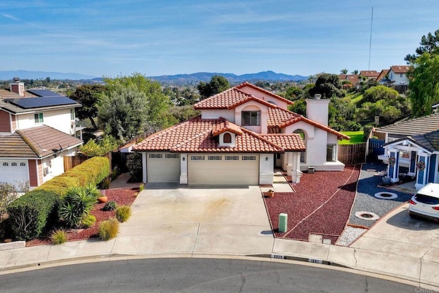 mediterranean / spanish house with a mountain view, a garage, a tiled roof, concrete driveway, and stucco siding