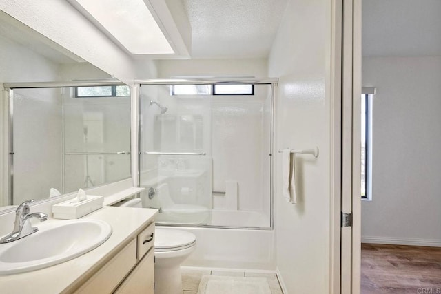 bathroom with shower / bath combination with glass door, toilet, vanity, a textured ceiling, and baseboards