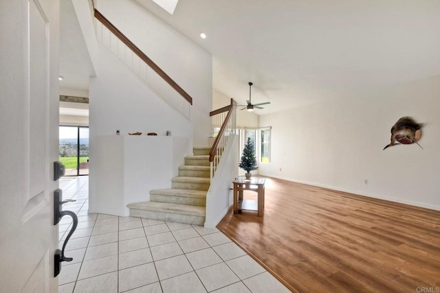 foyer entrance with stairs, high vaulted ceiling, a skylight, and a wealth of natural light