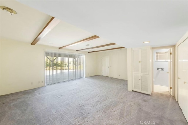 empty room with beamed ceiling and light colored carpet