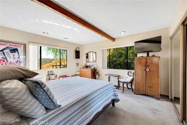 bedroom featuring beam ceiling and light colored carpet