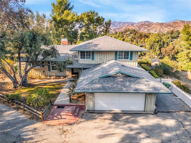 view of front facade with roof with shingles, fence, a mountain view, a garage, and driveway