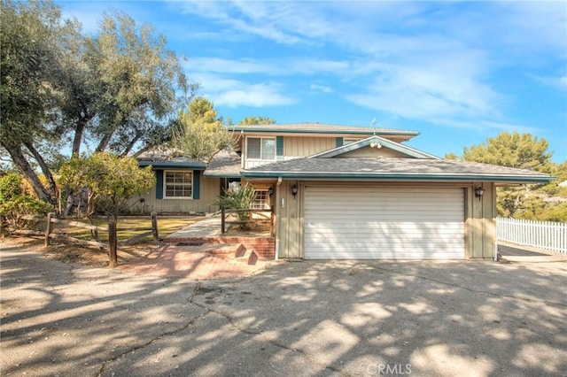 view of front of house featuring fence, driveway, and an attached garage