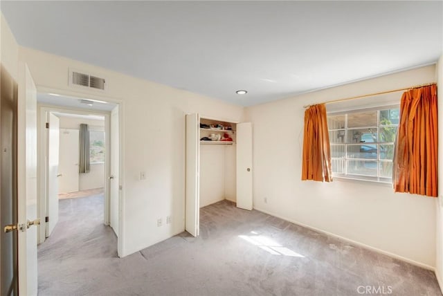 unfurnished bedroom with light carpet, a closet, and visible vents