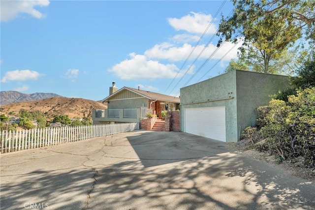 view of front of property with a fenced front yard, an outbuilding, stucco siding, concrete driveway, and a mountain view