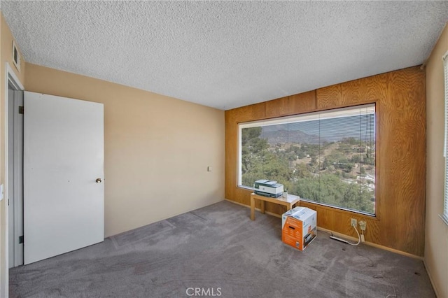 unfurnished room featuring carpet, visible vents, and a textured ceiling