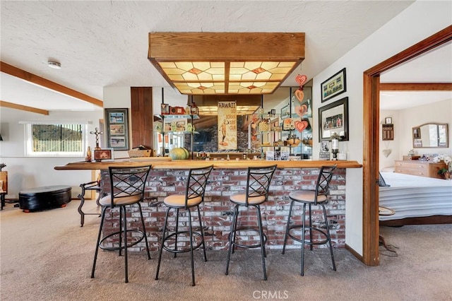 bar with a textured ceiling, beam ceiling, carpet flooring, and bar area