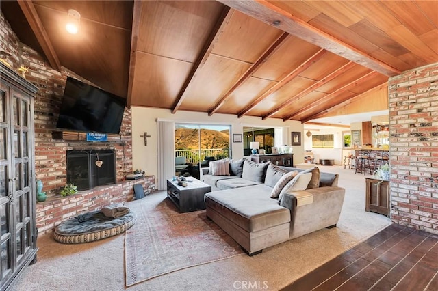 carpeted living area featuring vaulted ceiling with beams, a fireplace, and wood ceiling