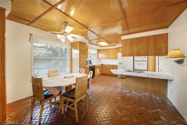 dining room featuring ceiling fan, brick floor, and baseboards