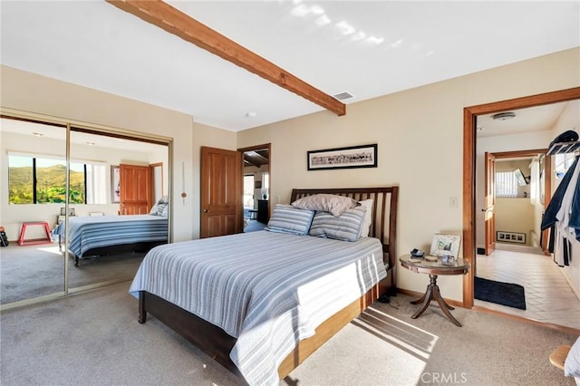 bedroom with light colored carpet, visible vents, baseboards, a closet, and beam ceiling