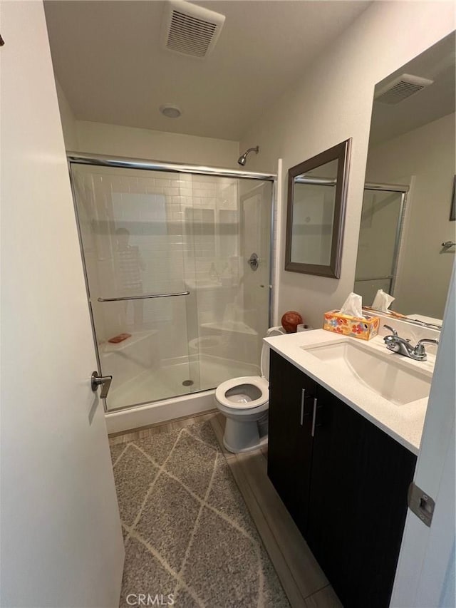 full bathroom with visible vents, a shower stall, toilet, and vanity