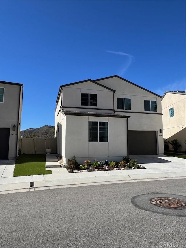 view of front of house with a mountain view, a garage, fence, concrete driveway, and stucco siding