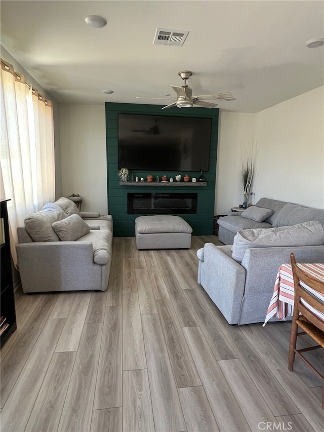 living area featuring ceiling fan, visible vents, and light wood-style floors