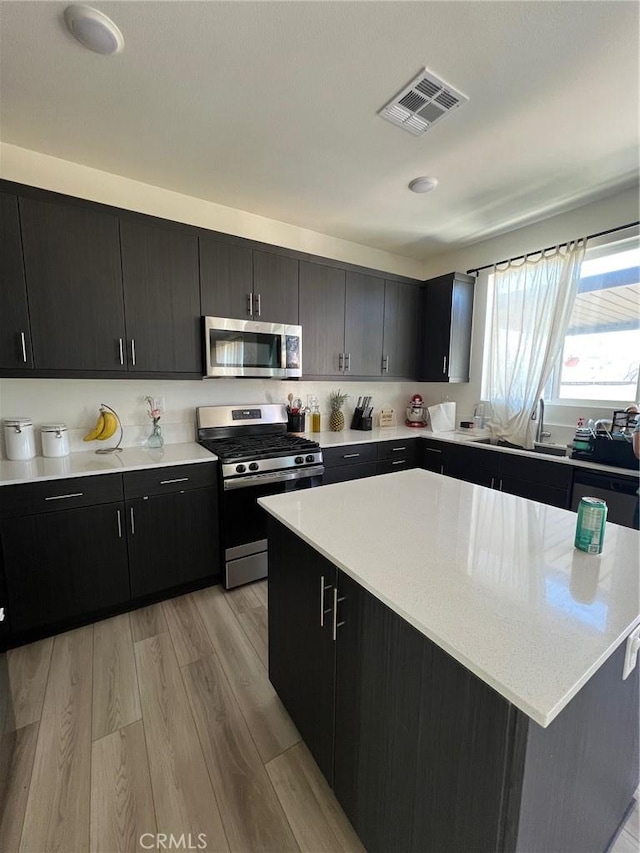 kitchen with a sink, visible vents, light countertops, appliances with stainless steel finishes, and dark cabinetry