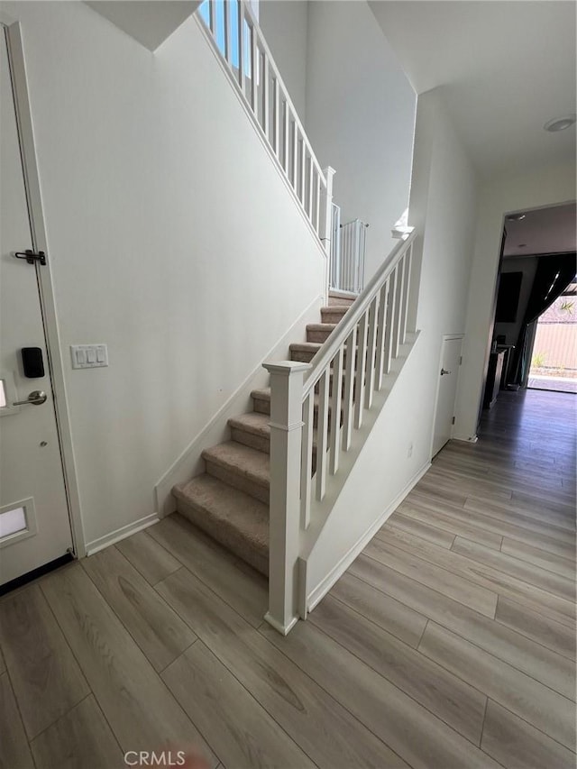 staircase featuring wood finished floors and baseboards