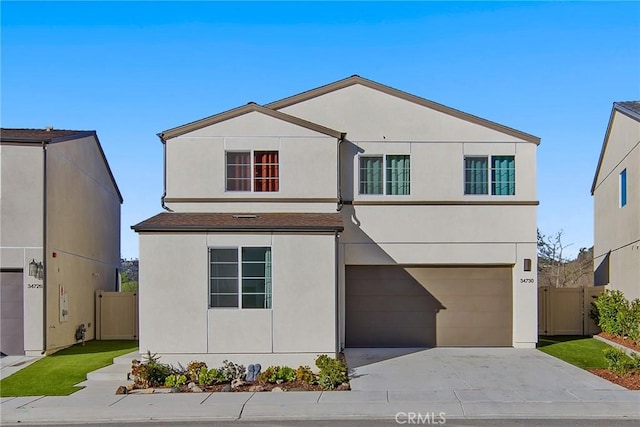 traditional-style house with an attached garage, fence, driveway, and stucco siding