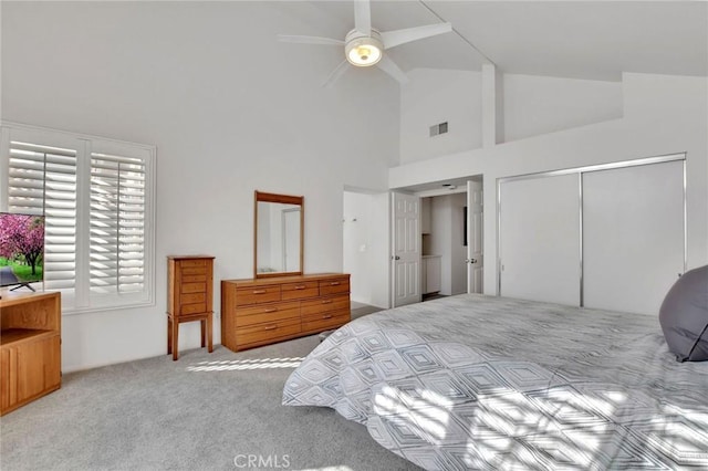 bedroom with a closet, visible vents, a ceiling fan, light carpet, and high vaulted ceiling