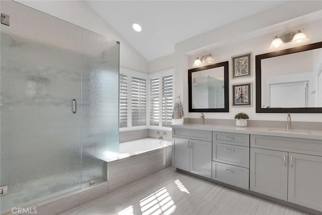 full bathroom featuring a stall shower, lofted ceiling, a sink, and a bath