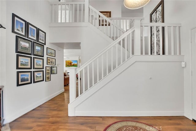 stairs featuring baseboards, a high ceiling, and wood finished floors