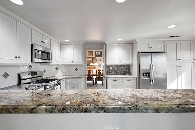 kitchen featuring light stone counters, recessed lighting, stainless steel appliances, white cabinetry, and decorative backsplash