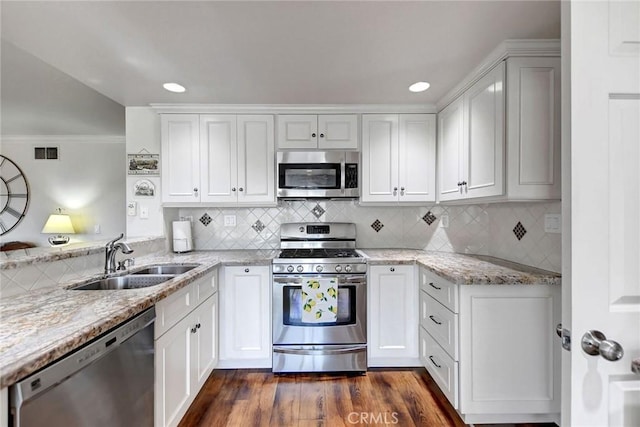 kitchen with visible vents, white cabinets, light stone countertops, stainless steel appliances, and a sink