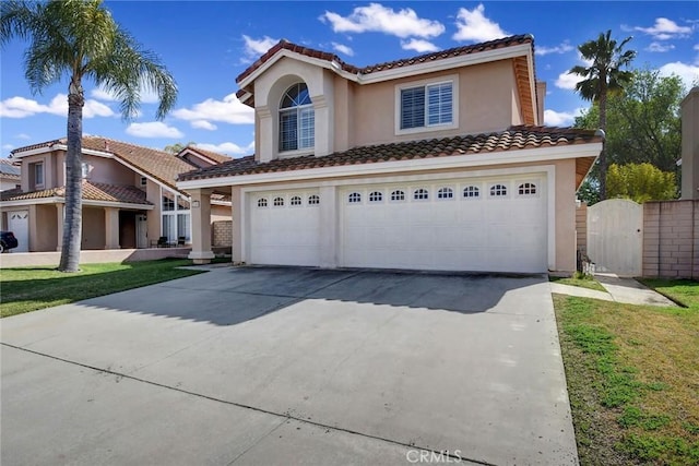 mediterranean / spanish-style home featuring a garage, concrete driveway, a gate, stucco siding, and a front lawn